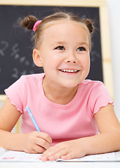 Image showing Little girl is writing using a pen