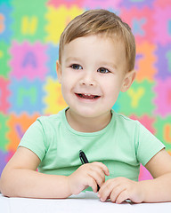 Image showing Little boy is writing on his copybook