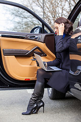 Image showing woman sitting on the threshold of the car
