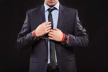 Image showing man in a business suit with leather bound with handcuffs. sex Toys