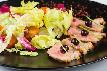 Image showing grilled meat with lettuce. on black plate