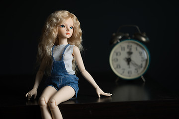 Image showing doll on the background of the old clock.