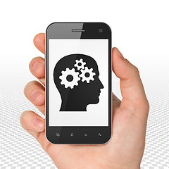 Image showing Business concept: Hand Holding Smartphone with Head With Gears on display