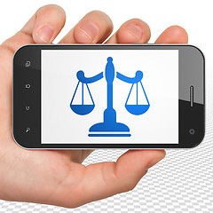 Image showing Law concept: Hand Holding Smartphone with Scales on display