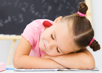 Image showing Little girl is sleeping on her writing-book