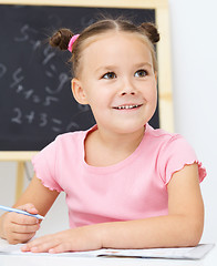 Image showing Little girl is writing using a pen