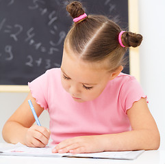 Image showing Little girl is writing using a pen