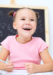 Image showing Little girl is writing using a pen