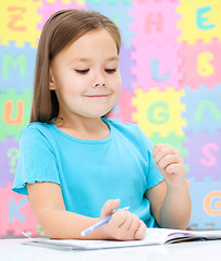 Image showing Little girl is writing using a pen