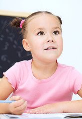 Image showing Little girl is writing using a pen