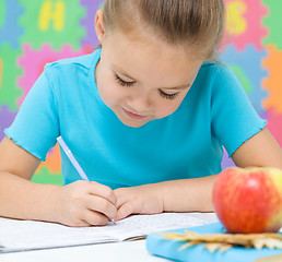 Image showing Little girl is writing using a pen