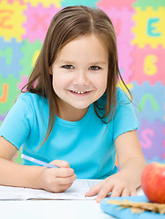 Image showing Little girl is writing using a pen