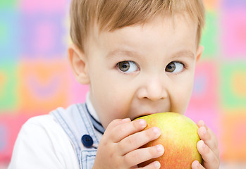 Image showing Little child is biting red apple