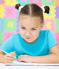 Image showing Little girl is writing using a pen