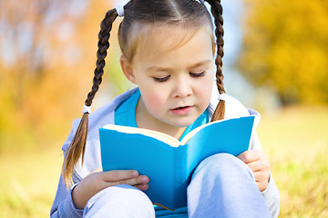 Image showing Cute little girl reads a book