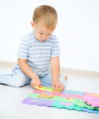 Image showing Little boy is putting together a big puzzle