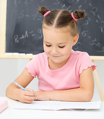 Image showing Little girl is writing using a pen