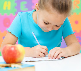 Image showing Little girl is writing using a pen