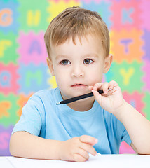 Image showing Little boy is writing on his copybook