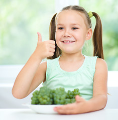 Image showing Cute little girl is eating green grapes