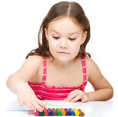 Image showing Little girl is drawing using colorful crayons