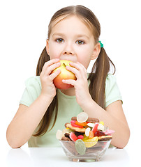 Image showing Little girl choosing between apples and sweets