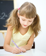 Image showing Little girl is writing using a pen