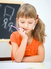 Image showing Little girl is writing using a pen