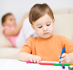 Image showing Little boy is drawing on white paper