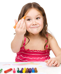 Image showing Little girl is drawing using colorful crayons