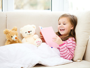 Image showing Little girl is reading a story for her teddy bears