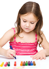 Image showing Little girl is drawing using a crayon