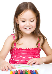 Image showing Little girl is drawing using colorful crayons