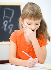 Image showing Little girl is writing using a pen