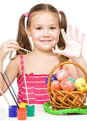 Image showing Little girl is painting eggs preparing for Easter