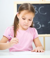 Image showing Little girl is writing using a pen