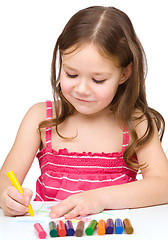 Image showing Little girl is drawing using colorful crayons