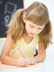 Image showing Little girl is writing using a pen