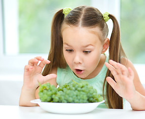 Image showing Cute little girl is eating green grapes