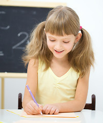 Image showing Little girl is writing using a pen