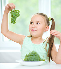 Image showing Cute little girl is looking at green grapes