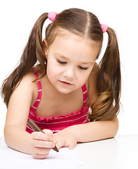 Image showing Little girl is drawing using a crayon