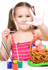 Image showing Little girl is painting eggs preparing for Easter