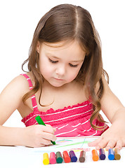 Image showing Little girl is drawing using a crayon