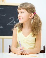 Image showing Little girl is writing using a pen