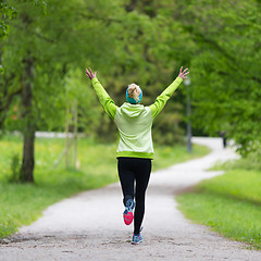 Image showing Sporty young female runner in city park.