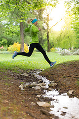 Image showing Sporty young female runner in city park. 