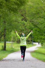 Image showing Sporty young female runner in city park.