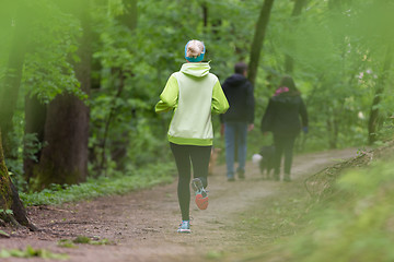 Image showing Sporty young female runner in the forest. 