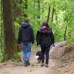 Image showing Couple walking their two dogs in forest